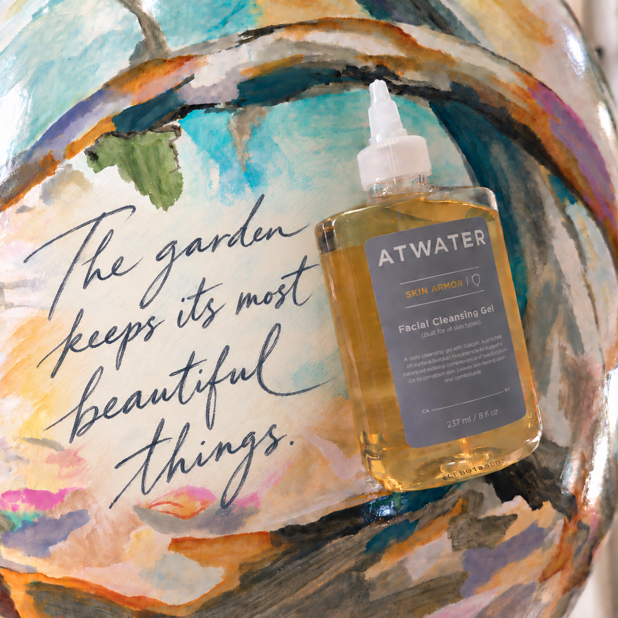 A bottle of ATWATER facial cleansing gel placed on a colorful painted surface with the phrase 'The garden keeps its most beautiful things.' written in script.